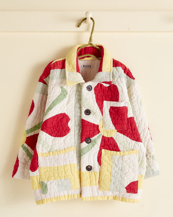 The Heart Flower Kids' Jacket - OS, resembling an antique quilt jacket with vibrant colors and various floral patterns, hangs on a white hook against a cream background. This Baby Bode jacket features a collar, front buttons, and patch pockets.