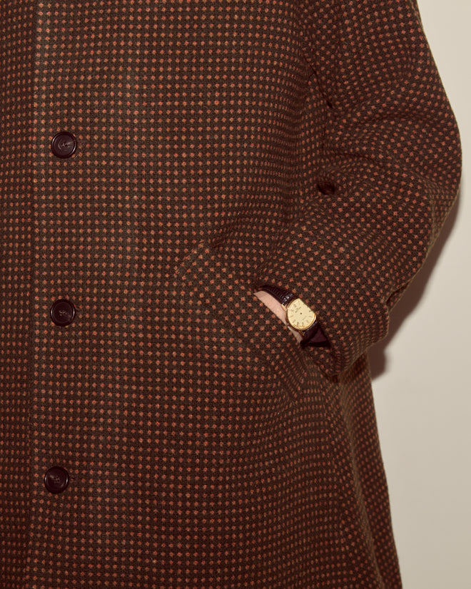 A person wearing the Hedgerow Coat in green, with one hand in their pocket and a gold wristwatch visible.