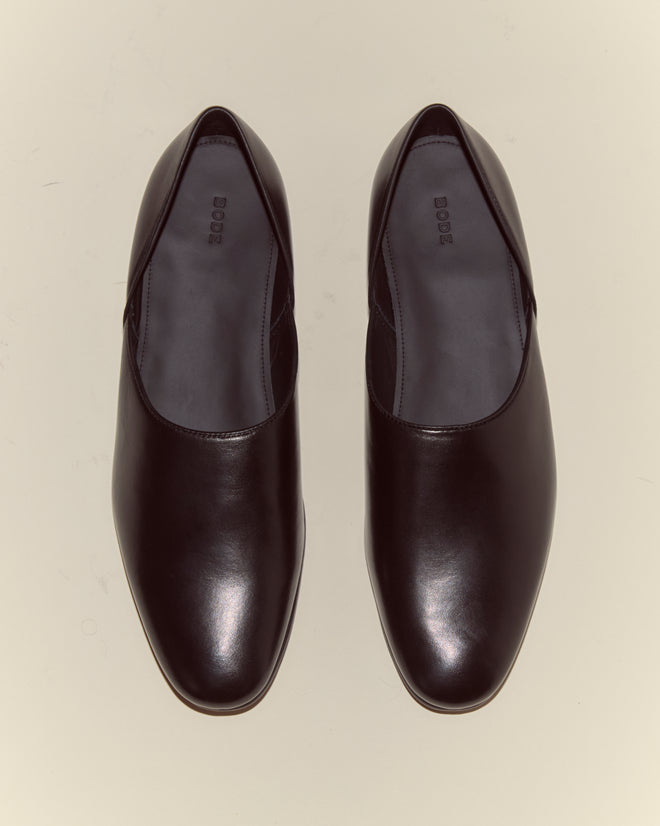 A pair of Leather House Shoes - Black, crafted in Italy from Napa leather, is shown from above on a light background.