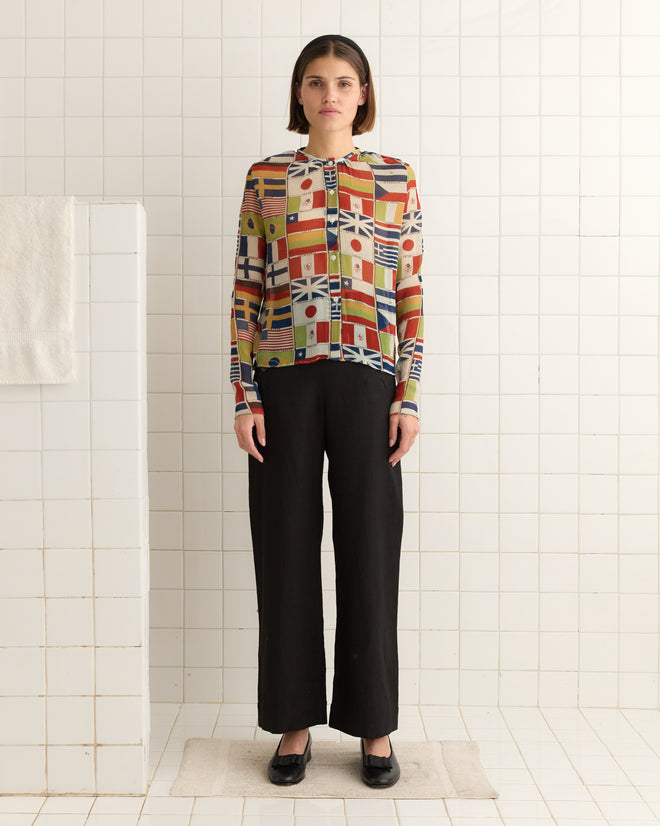 A person in an International Blouse and black pants stands in a tiled room, facing forward.