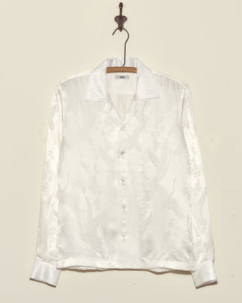 The Ivory Cloud Long Sleeve Shirt, crafted from deadstock jacquard with a subtle embossed pattern in white satin, is made in New York and displayed on a metal hook.