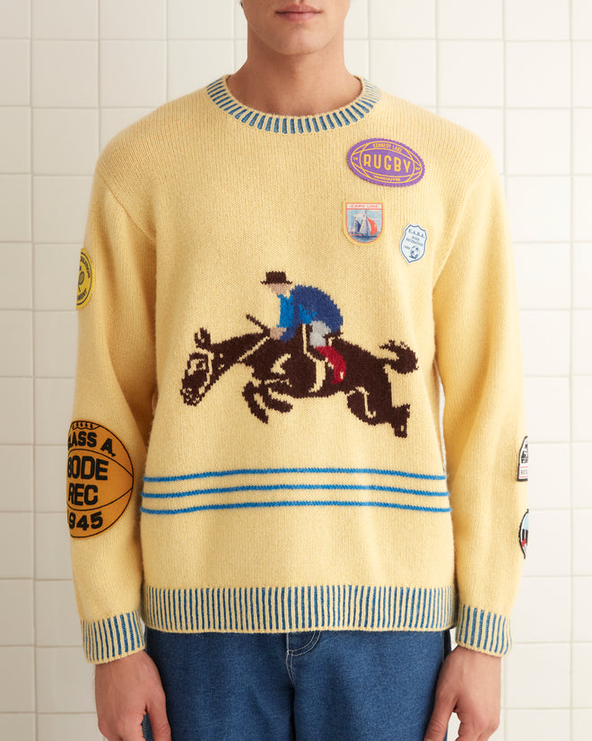 A person is wearing the lively Jockey Sweater from the 1980s, paired with blue jeans in a tiled room.