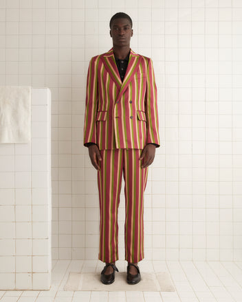 A person in a Juniper Stripe Double-Breasted Suit Jacket stands in a tiled room next to a white towel.