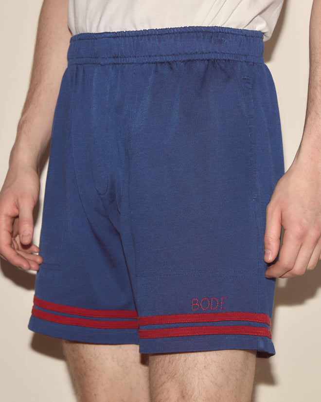 A person wears Lakewood Shorts—blue cotton-rayon with red stripes and 