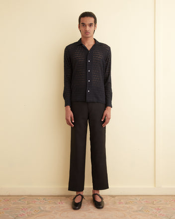 Person standing against a beige wall, wearing the Lattice Lace Long Sleeve Shirt in black, paired with black pants and black shoes.