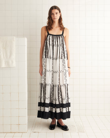 Black and white cotton dress with black-and-white embroidered roses and stripes of satin ribbon. The dress has a contrast collar and hem and an unfitted silhouette.