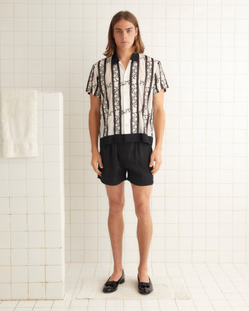 Black and white cotton shirt with black-and-white embroidered roses and stripes of satin ribbon. The shirt has a contrast collar and hem and an unfitted silhouette.