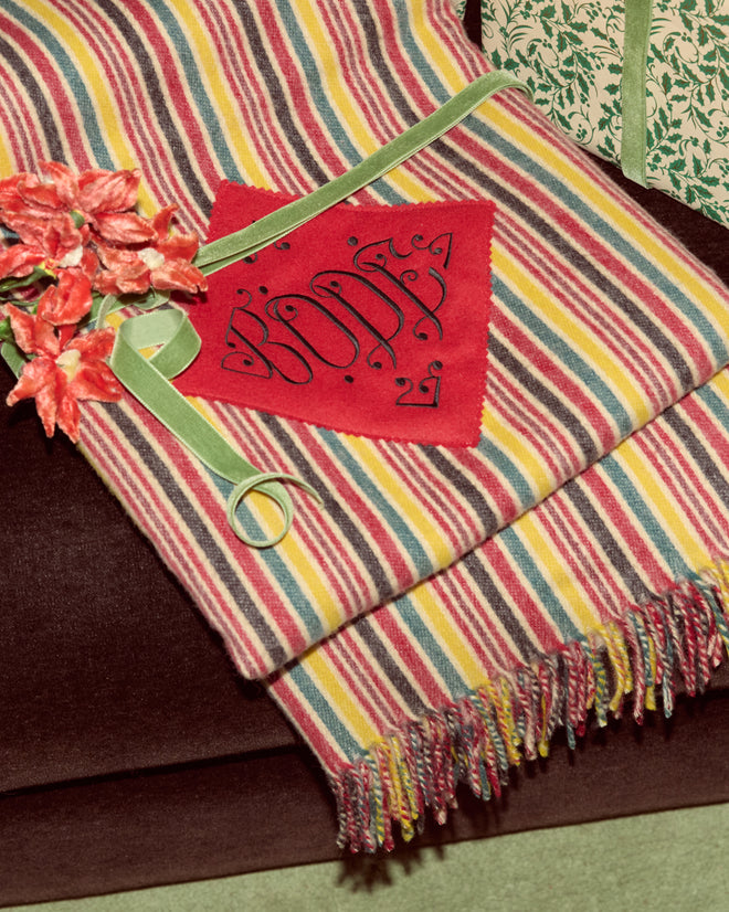 Lawrence Throw Blanket with a classic stripe pattern, fringe, red “1967” felt patch, green ribbon, and red artificial flowers.