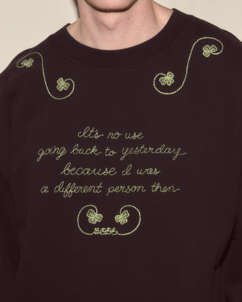 Wearing the Lucky Draw Pullover: a black 100% cotton sweatshirt with yellow cursive text, decorative hand embroidery on the front and shoulders, plus subtle card suit motif accents.