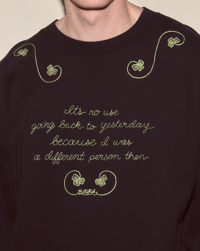 Wearing the Lucky Draw Pullover: a black 100% cotton sweatshirt with yellow cursive text, decorative hand embroidery on the front and shoulders, plus subtle card suit motif accents.