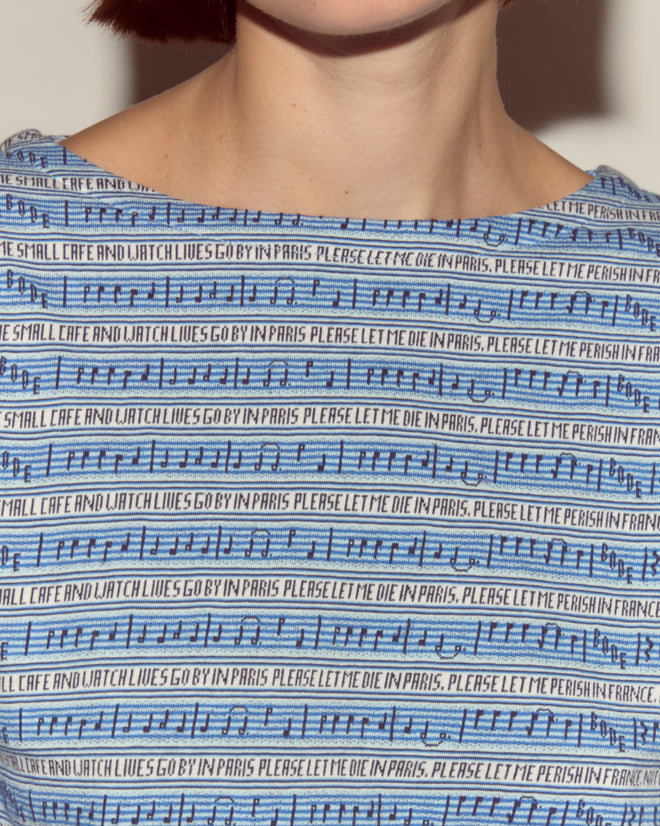 Close-up of the Lyric Long Sleeve in blue, featuring black musical notes, jacquard stripes, and repeated text: "PLEASE LET ME DIE IN PARIS.