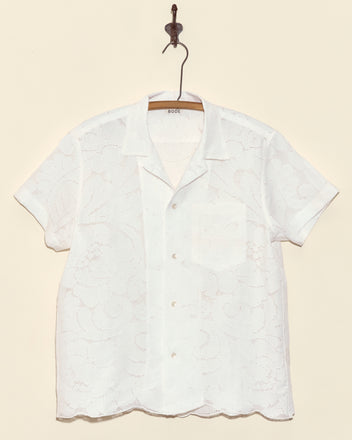 Magnolia Branch Short Sleeve Shirt - M: A white lace button-up displayed on a hanger against a beige background, this unique vintage-inspired shirt brings timeless charm to your wardrobe.
