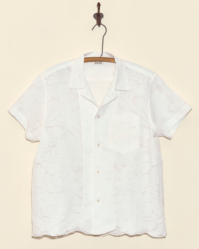 Magnolia Branch Short Sleeve Shirt - M: A white lace button-up displayed on a hanger against a beige background, this unique vintage-inspired shirt brings timeless charm to your wardrobe.