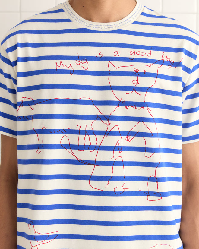 Someone wears the Margate Tee, featuring blue and white stripes with charming red dog hand drawings and the playful text "My dog is a good boy.