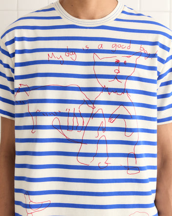 Someone wears the Margate Tee, featuring blue and white stripes with charming red dog hand drawings and the playful text 
