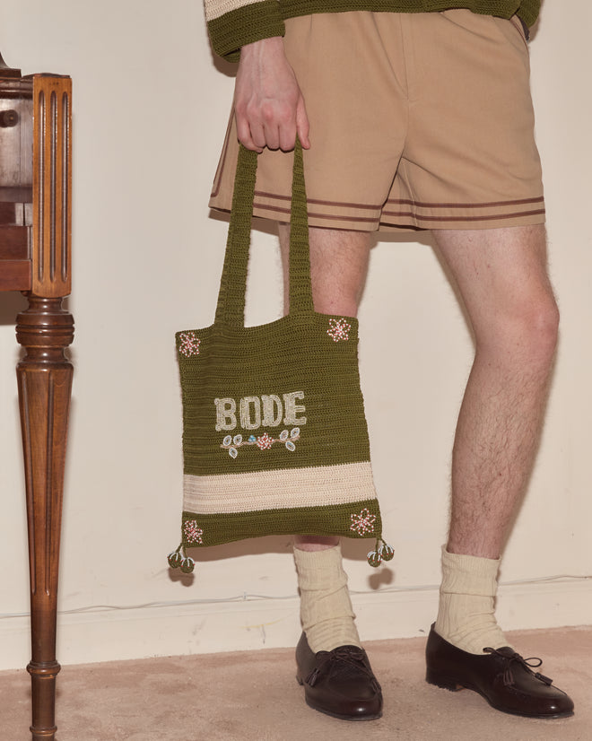 A person in shorts holds the Marsh Crochet Tote, a green bag with 