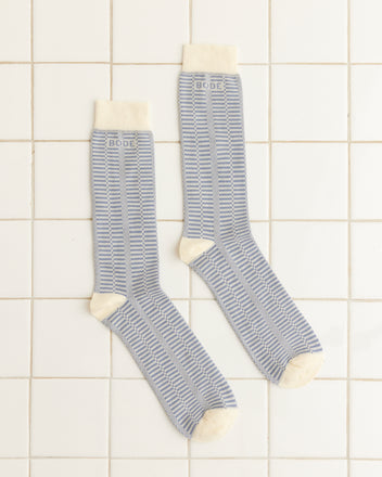 A pair of Micro Check Socks - Blue/Cream with cream toes and cuffs, laid flat on a white tiled floor.