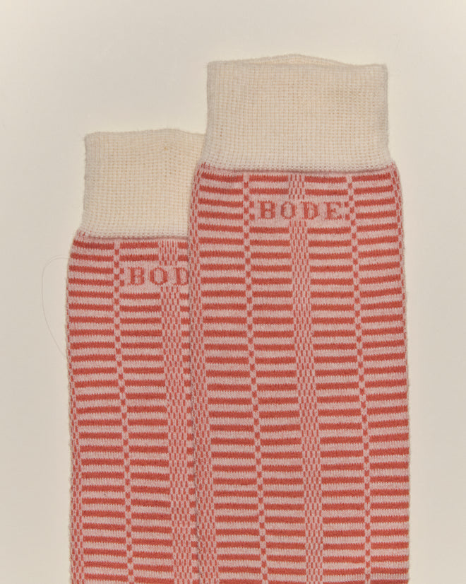 The Micro Check Socks in Peach/Cream, featuring a checkered pattern and "BODE" text near the top, are laid flat on a light background and evoke vintage children's socks and classic style.
