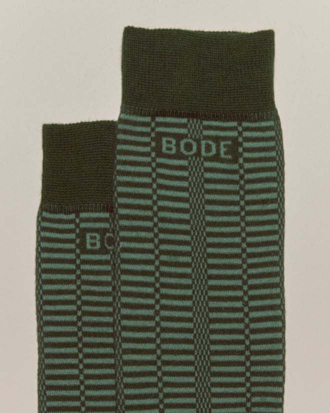 Two Micro Check Socks - Green by BODE, featuring green and black stripes with "BODE" text near the cuffs, inspired by 1960s vintage children's socks, laid side by side.