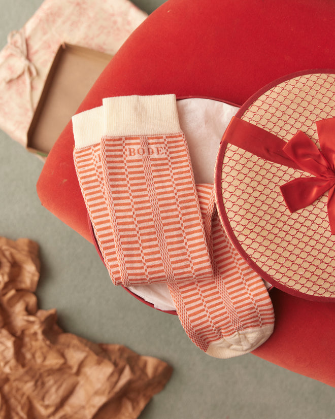 A pair of Micro Check Socks - Peach/Cream in vintage style, featuring pink and white stripes with white cuffs, toes, and heels, laid out on a light-colored surface. Made in Italy with a charming check pattern.