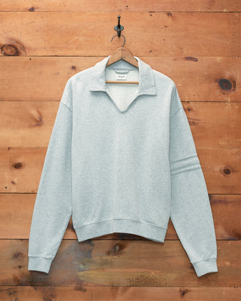 Heathered Grey Crew Polo, made from 100% cotton, featuring a collared pullover design and displayed against a wooden wall background.