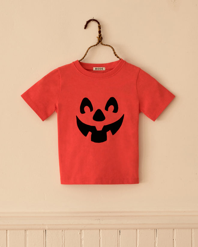 Pumpkin Kids’ Tee featuring a red short-sleeved shirt with a black jack-o’-lantern face print.