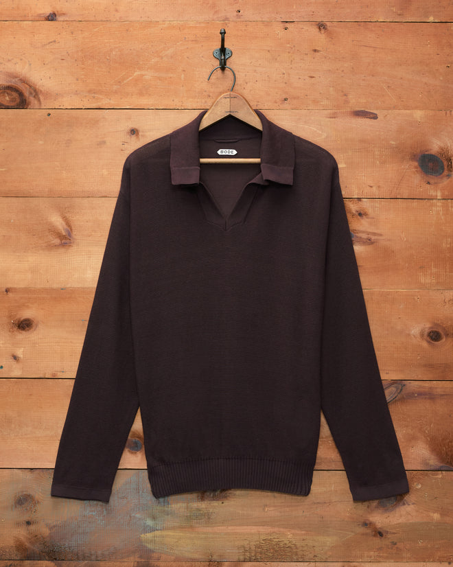 Boxy Long Sleeve Polo - Brown knit sweater with an open collar, featuring a boxy silhouette inspired by classic 1970s polos, displayed on a wooden hanger against a rustic wood wall.