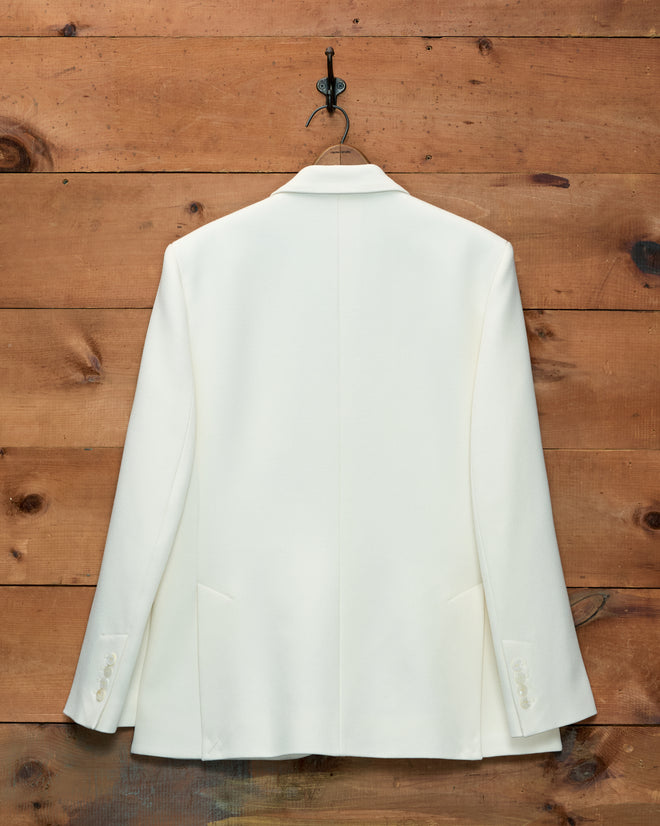 Back view of a cream Riding Twill Suit Jacket hanging on a wall hook.