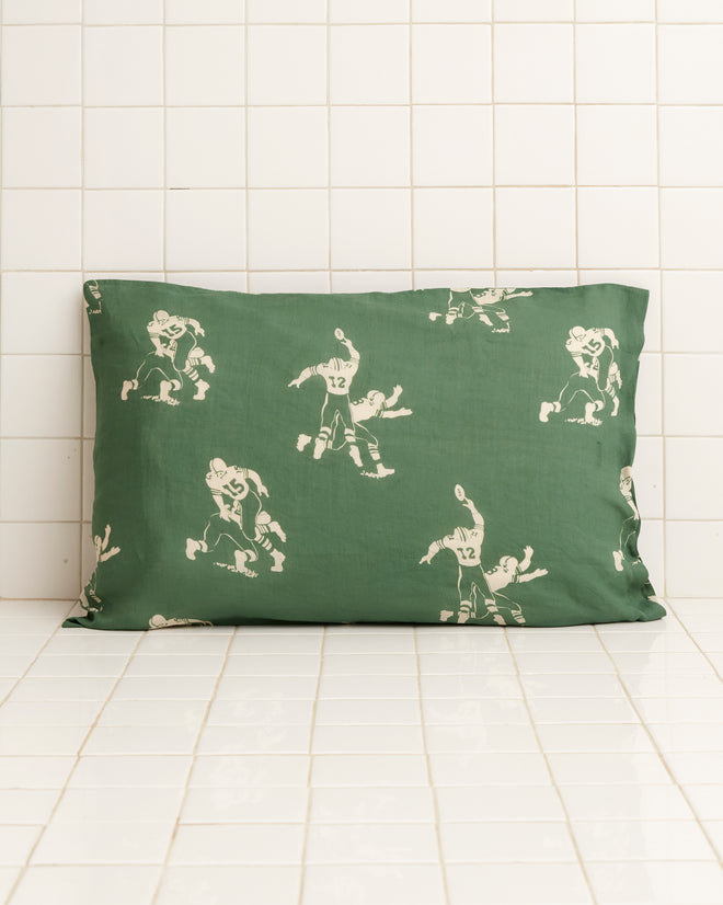 Introducing our Football Silhouette Pillowcases in green and cream, featuring a nostalgic 1930s-inspired design with illustrations of football players set against a white tiled background.