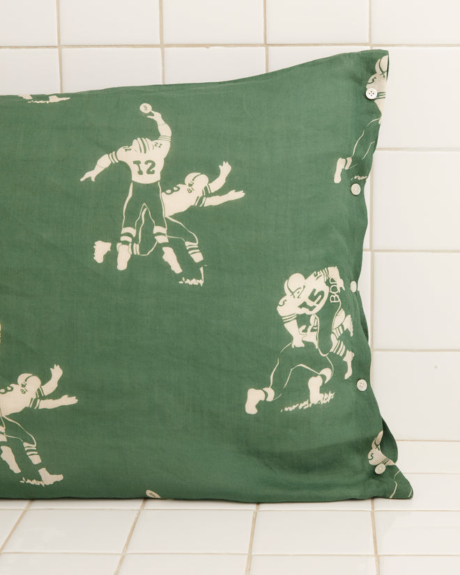 Introducing our Football Silhouette Pillowcases in green and cream, featuring a nostalgic 1930s-inspired design with illustrations of football players set against a white tiled background.