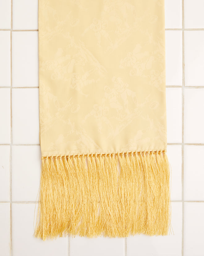 The Football Jacquard Scarf in yellow, crafted from a silk-viscose blend and featuring fringe detailing, is elegantly knotted and laid flat on a white tiled surface.