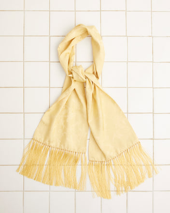 The Football Jacquard Scarf in yellow, crafted from a silk-viscose blend and featuring fringe detailing, is elegantly knotted and laid flat on a white tiled surface.