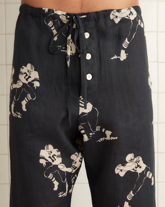 Black linen pajama pants, images of football players across the garment with drawstring tie at the waist.