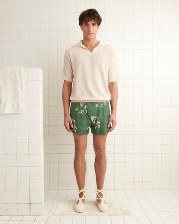 Green linen boxer shorts images of football players across the garment. Features elastic side bands and a two button front closure.