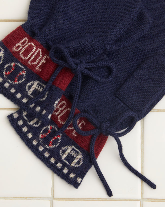 Sporting Jacquard Mittens in navy blue featuring red cuffs and a white pattern, crafted from soft baby alpaca, displayed on a white tiled surface.