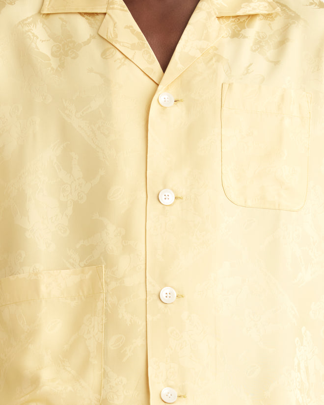 Close-up of the Football Jacquard Short Sleeve Louie Shirt in Yellow, featuring a buttoned design with an intricate pattern of football players, two front pockets, and a style reminiscent of the 1950s-1960s.