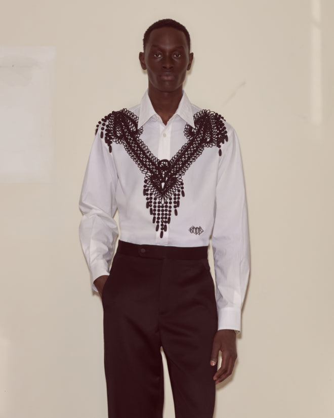 Person wearing the Jet Braid Collar, a white shirt featuring a black lace collar, paired with black pants against a plain background.