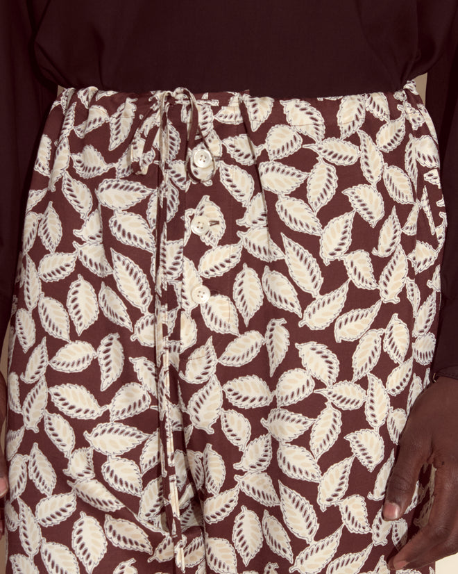 Close-up of Paper Birch Pajama Pants—viscose trousers with white leaf prints on maroon, featuring a waist tie for comfort and a touch of Peter Pan whimsy to your loungewear.
