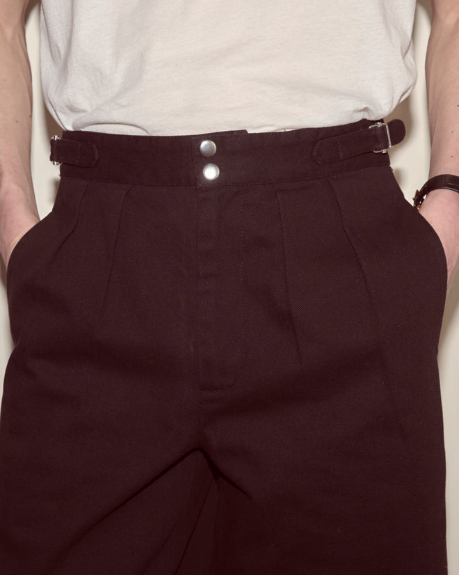 A person wears Wide Leg Snap Trousers - Black, with hands in pockets and a white shirt tucked in.