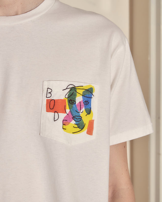 The Portrait Pocket Tee is a white pocket t-shirt featuring a vibrant Modernist-inspired abstract face design and "BODE" printed on the chest pocket.