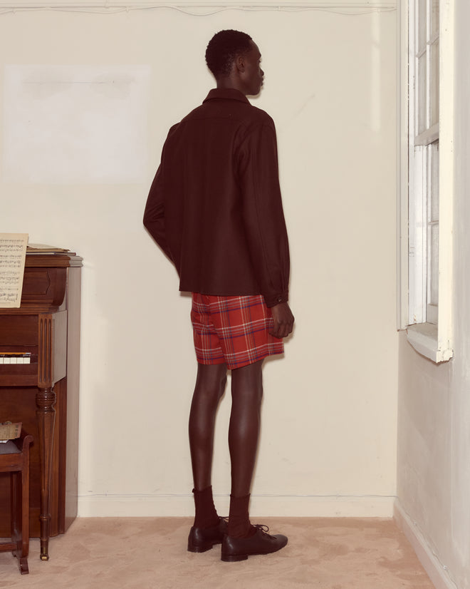 A person wears the Bramble Franck Jacket, standing by a window and piano, channeling 1960s workwear style.