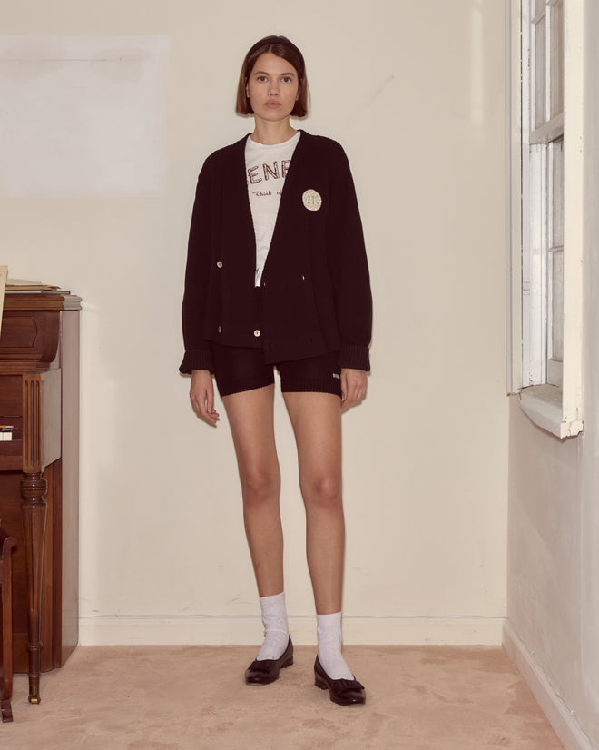 Woman wearing the Double-Breasted Cardigan in black with an embellished circle brooch