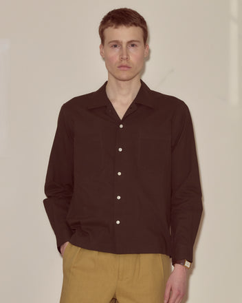 A man wearing the Voile Long Sleeve Shirt in brown stands against a plain light background, looking at the camera.