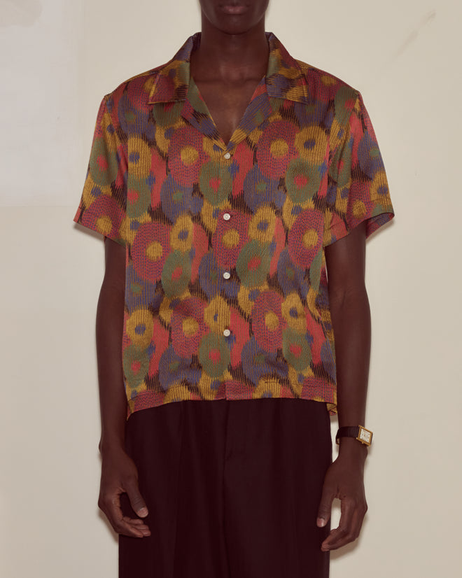 Person wearing the Fruit Pit Short Sleeve Shirt, a colorful button-up featuring a bold abstract floral pattern inspired by a French swatchbook with touches of silk seersucker.