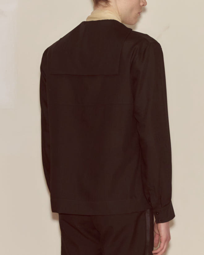 A person in a black Shadow Cricket Shirt and pants is standing with their back to the camera.