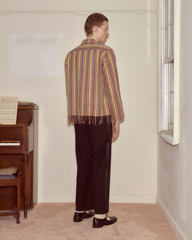 Wearing a Lawrence Overshirt and black pants, a person stands facing a wall beside a piano in a softly lit room.