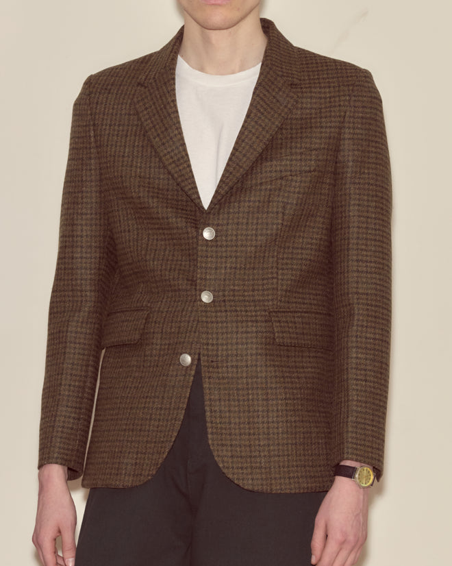 Person wearing a Morris Houndstooth Suit Jacket, white t-shirt, black pants, and a wristwatch, standing against a plain background.