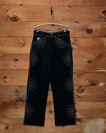 Silver Stud Knolly Brook Trousers in black cotton twill, hanging on a wooden hanger with silver stud starbursts.