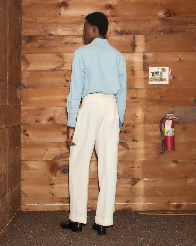 A person from behind wearing a light blue button-down shirt and cream-colored wide-leg Riding Twill McNab Trousers.