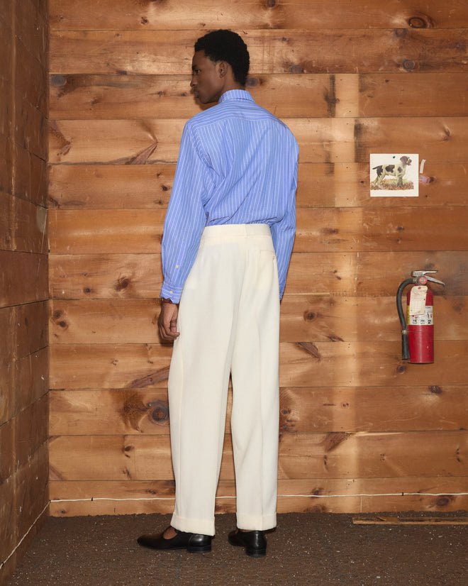 Man in a blue striped button-down shirt and cream-colored Riding Twill McNab Trousers.